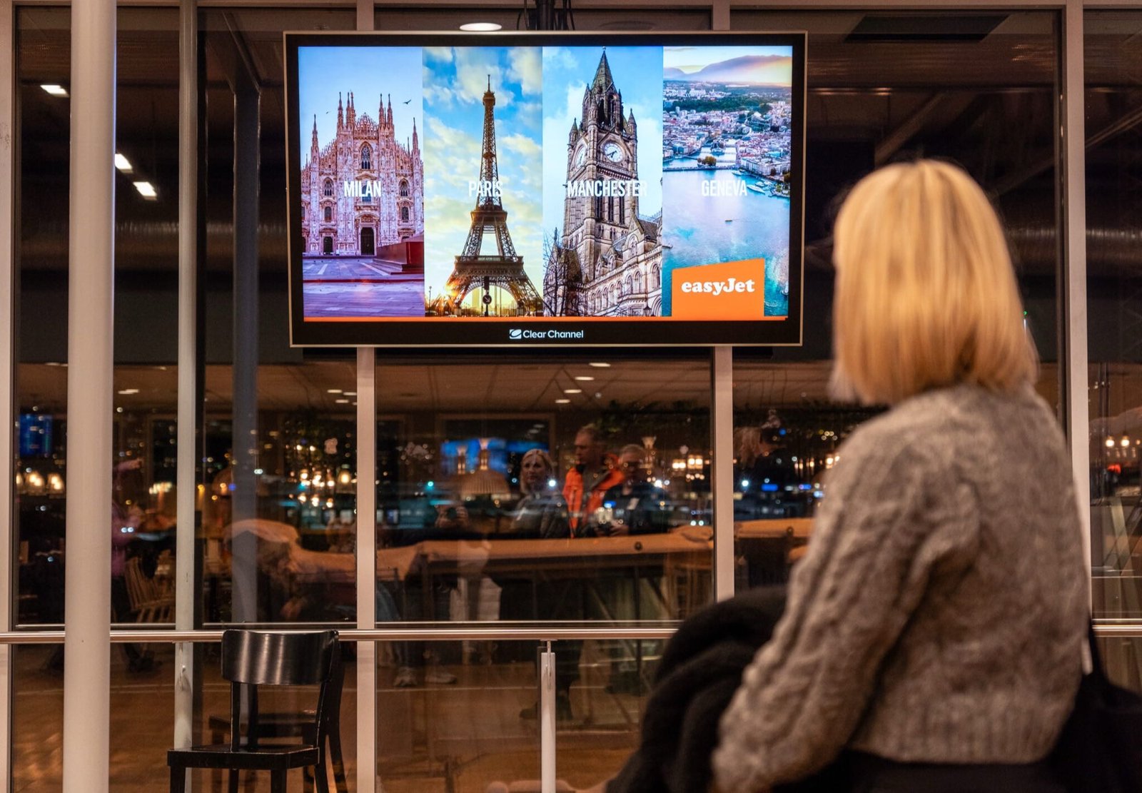 En reisende ser på en reklamefilm på infokanalen i flyplassterminalen